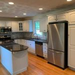 A kitchen with white cabinets and stainless steel appliances featured in a house painting photo gallery.