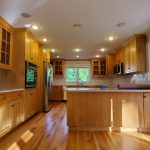 A house painting photo gallery showcasing a kitchen with wood cabinets and hardwood floors.