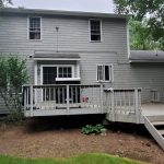 A gray house showcasing a deck and a grill, perfect for a house painting photo gallery.