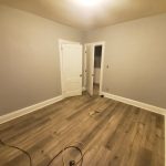 An empty room with wood floors and a door, perfect for a house painting photo gallery.