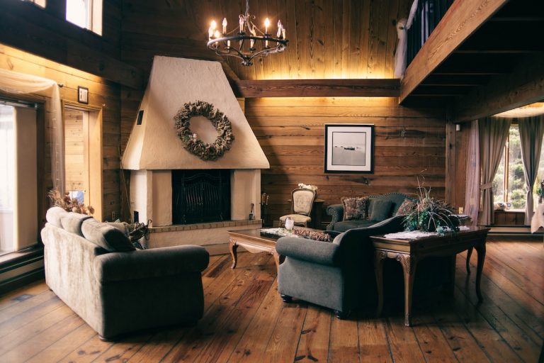 Rustic living room with painted white stucco fireplace wood plank walls vaulted ceiling and hardwood floors in a New England home