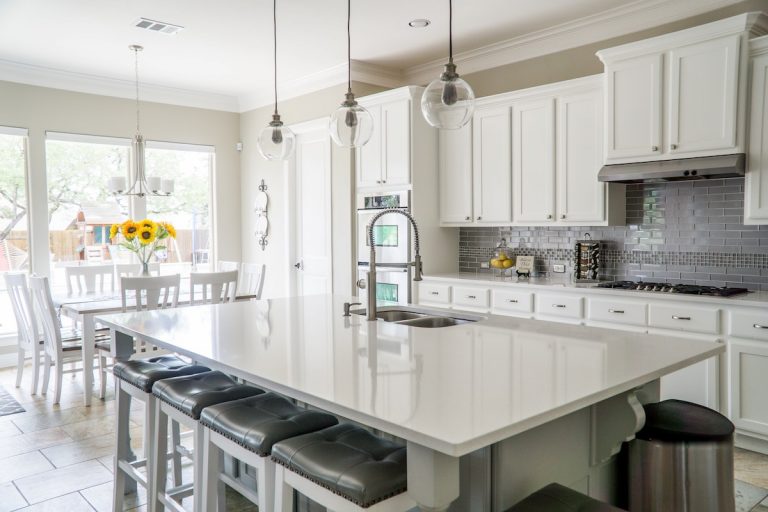 Bright open kitchen with cabinet refinishing in white gray subway tile backsplash quartz island and glass pendant lights in a Rhode Island home