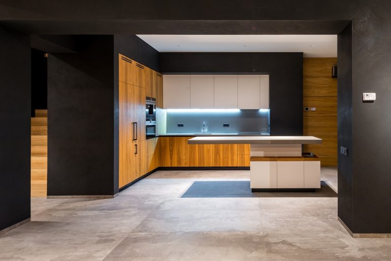 Dramatic kitchen with matte black painted walls wood grain cabinetry white upper cabinets and LED under-cabinet lighting in a Rhode Island home