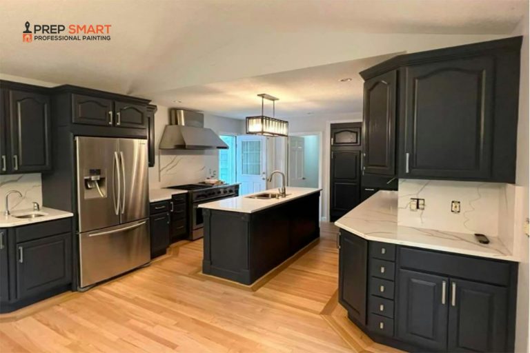 A kitchen in a commercial building with black cabinets and stainless steel appliances.
