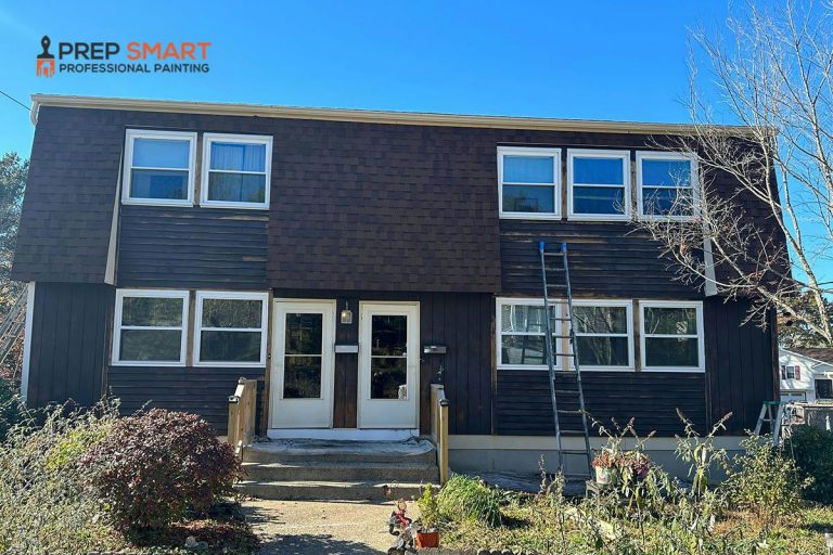 Two-story dark brown shingle siding home with a ladder against the exterior being prepped for a professional exterior painting project in Rhode Island