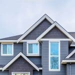 Two-story home with blue-gray siding, white trim, and gabled roof illustrating the best time to schedule exterior painting in Providence