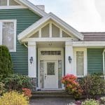 Home exterior with green siding and white trim surrounded by spring landscaping ready for exterior painting